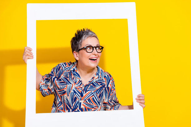 照片中迷人的退休妇女看起来空的瞬间相框穿着时尚的彩色衣服孤立在黄色的背景图片下载