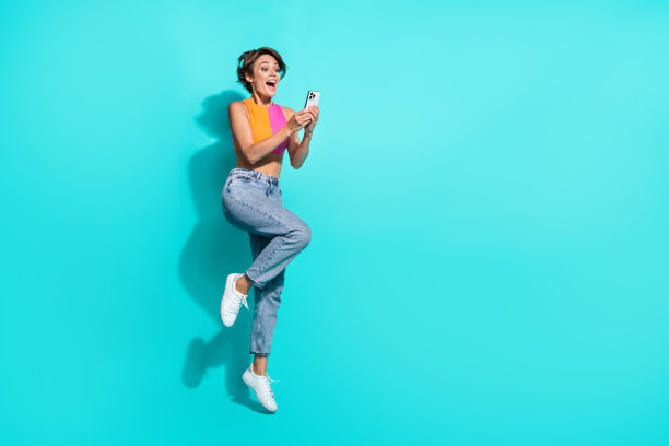 漂亮兴奋的女人全身照片穿粉红色的橙色顶部跳高聊天装置空的空间孤立的蓝绿色背景图片下载