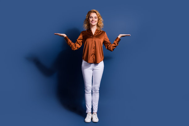 可爱的积极的女孩穿丝绸衬衫的全尺寸照片展示产品在手臂上的空白空间孤立在深蓝色的背景图片下载