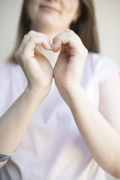 女性双手交叠成心形，照片中没有脸部，对焦柔和，色彩细腻。图片下载
