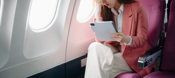 一位沮丧的女士坐在飞机上，双手抱头的照片。一位亚洲女士坐在座位上图片下载