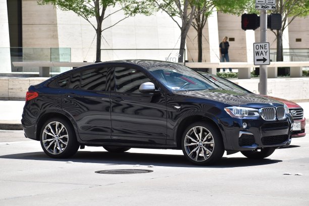 一辆蓝色的宝马X6 SUV驶过市中心金融区的一个十字路口图片下载