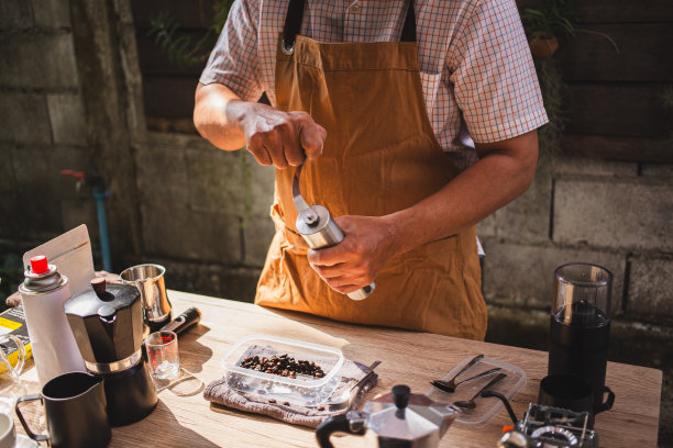 在一个质朴的户外cafÃ©设置，一个人正在准备一个新鲜的咖啡研磨烘焙阿拉比卡咖啡豆到一个手工不锈钢研磨机图片下载