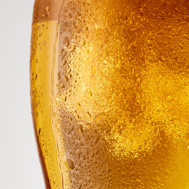 冷饮的特写照片，啤酒与厚厚的白色泡沫的灰色工作室背景。图片下载