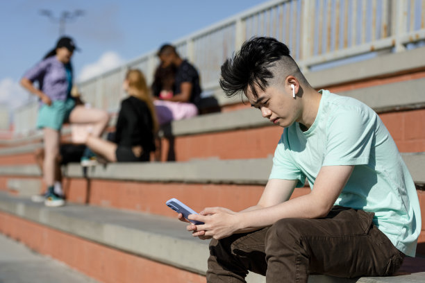 十几岁的男孩独自使用智能手机，远离朋友图片下载