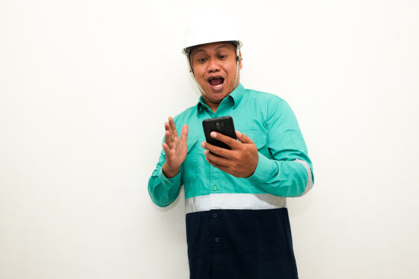 照片中，一名亚洲男子看着手中的手机，露出震惊的表情图片下载