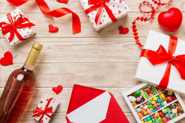情人节装饰购物的俯视图照片，包，酒，瓶子，信封，礼物，盒子，糖果和红色的心在彩色背景与空白的空间。帧的背景图片下载
