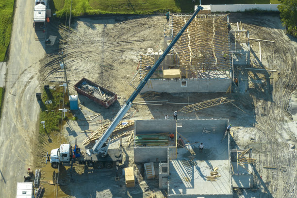 佛罗里达州农村地区，专业建筑商和起重机正在为未完工的郊区木结构房屋屋顶施工。美国的住房发展概念图片下载