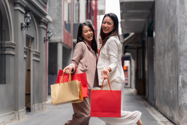 两个亚洲美女拿着购物袋，在城市购物中心的背景下，中国的新年节日图片下载