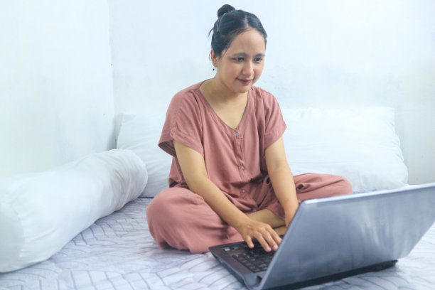 小女孩在床上用笔记本电脑工作。女商人，技术概念。居家办公图片下载