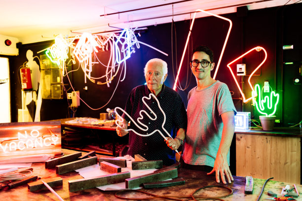 微笑的家族企业主在他们的工作室里摆着霓虹灯图片下载