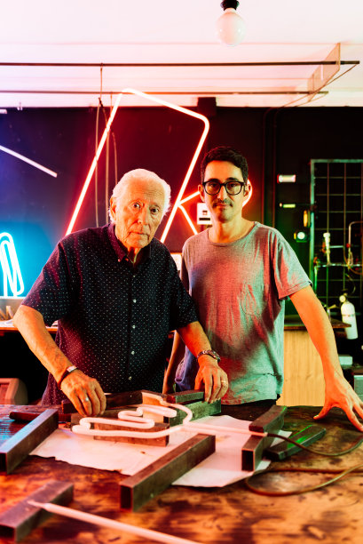 两代霓虹灯制造商在一个车间一起工作图片下载
