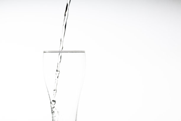 把水倒进白色背景的杯子里。特写图片，白色背景上的一杯饮用水，图片下载