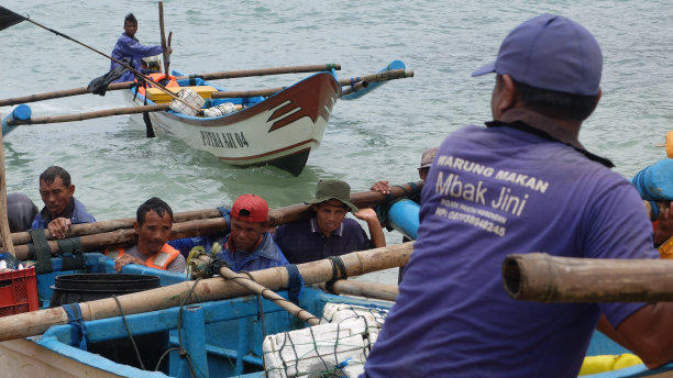 在Ngrenehan海滩上，一群渔民在公海上搜寻了一夜之后，将这艘船推向海滩。图片下载