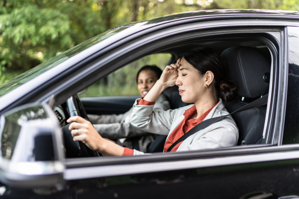 年轻的女商人在开车时头痛。图片下载