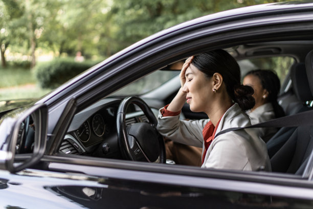 年轻的女商人在开车时头痛。图片下载