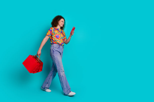 照片正面可爱的好女人穿着时尚的印花衣服，走路，背着包，订单交付孤立的青色背景图片下载