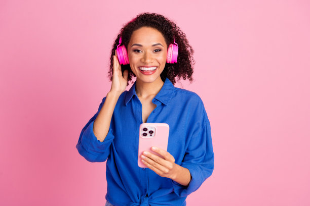 开朗可爱可爱的女人穿着时髦的衣服听音乐无线耳机孤立在粉红色的背景照片图片下载