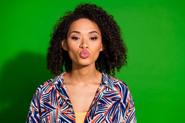 照片少女可爱的女士穿着印花衬衫送你吻孤立的绿色背景图片下载