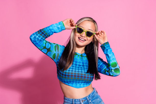 照片中闪亮女士穿着印花衬衫，深色眼镜微笑，空白空间孤立的粉红色背景图片下载