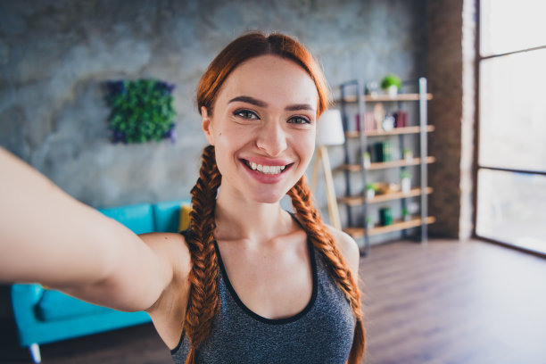 年轻漂亮的健身女孩笑容满面的照片使自拍运动服训练公寓室内图片下载