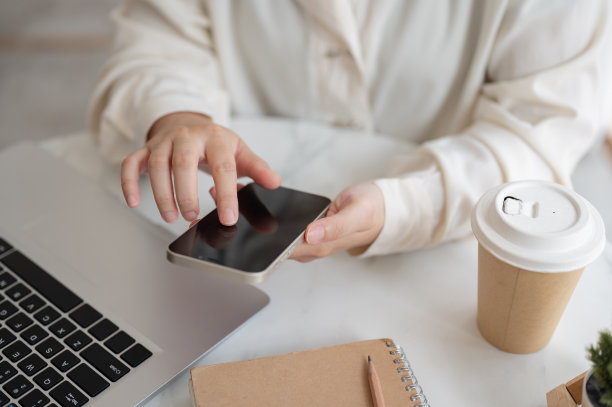 一位女商人坐在咖啡店的桌子上使用智能手机的特写照片。图片下载