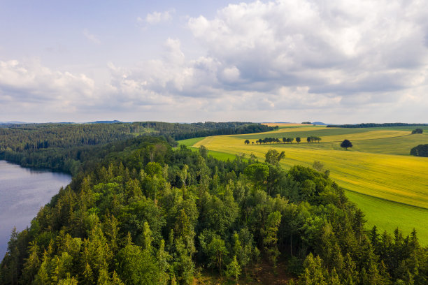 在一个阳光明媚的夏日，无人机拍摄的风景如画的乡村航拍照片。弯弯曲曲的河流，黄色的田野，茂密的森林。德国乡村景观图片下载