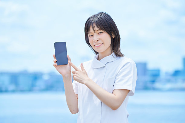 一名身穿白大褂的年轻女子正在操作智能手机图片下载