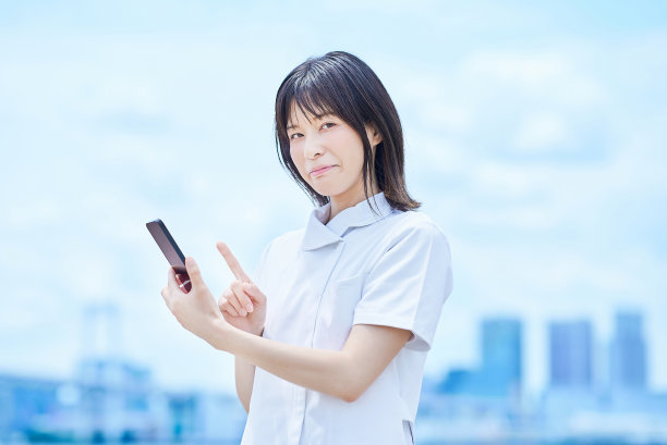 一名身穿白大褂的年轻女子正在操作智能手机图片下载