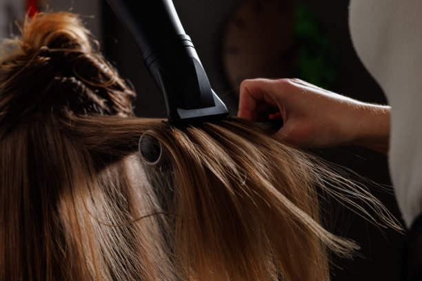 美发师在美容院用吹风机和梳子吹干头发，近距离吹干头发图片下载