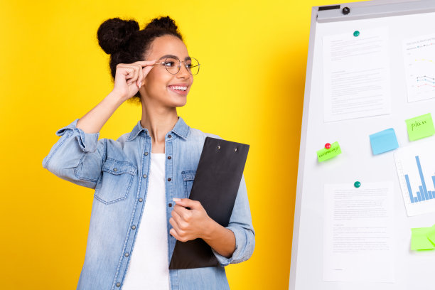 漂亮的年轻女孩的照片剪贴板看白板穿牛仔衬衫孤立的黄色背景图片下载