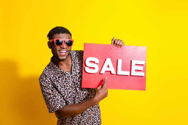 照片正面的好男人穿着时髦的衣服显示标牌夏季热销孤立的黄色背景图片下载