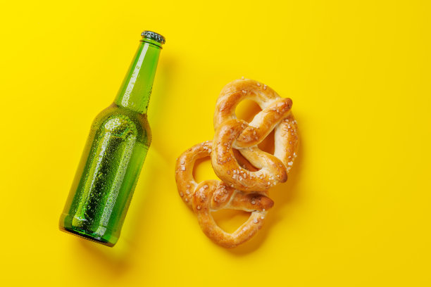 黄色背景上的啤酒瓶和椒盐脆饼图片下载