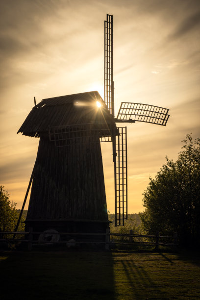 夕阳下古老的木制风车。垂直剪影照片图片下载