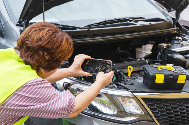 一辆打开的汽车引擎盖上的女性照片破裂了图片下载