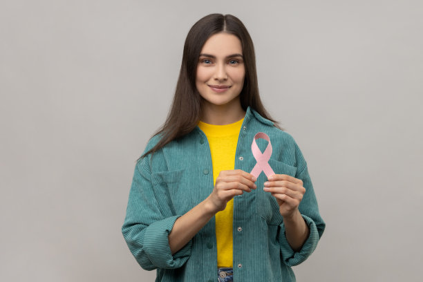 迷人的积极女性手持粉色丝带，象征乳腺癌意识，女性健康。图片下载