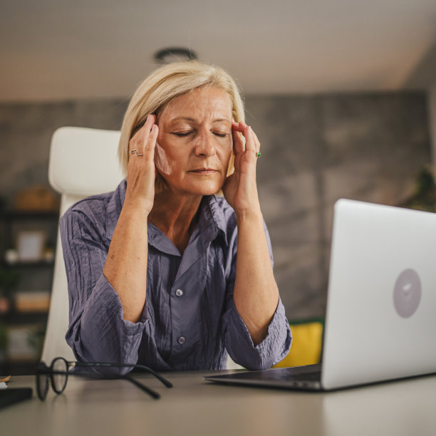 成熟的高级女性在家工作，患有偏头痛图片下载
