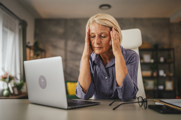 成熟的高级女性在家工作，患有偏头痛图片下载