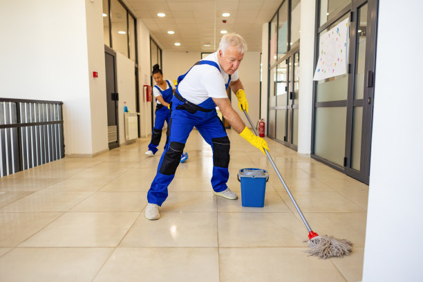 穿蓝色服装的看门人正在打扫学校地板图片下载