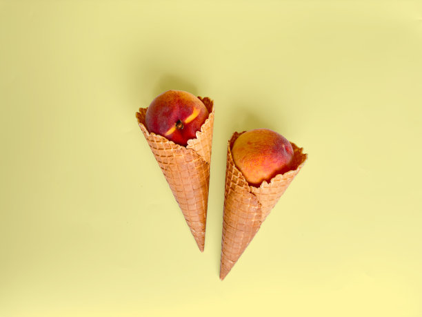 两个冰淇淋甜筒，在柔和的背景上填满桃子。最小的概念。本空间图片下载