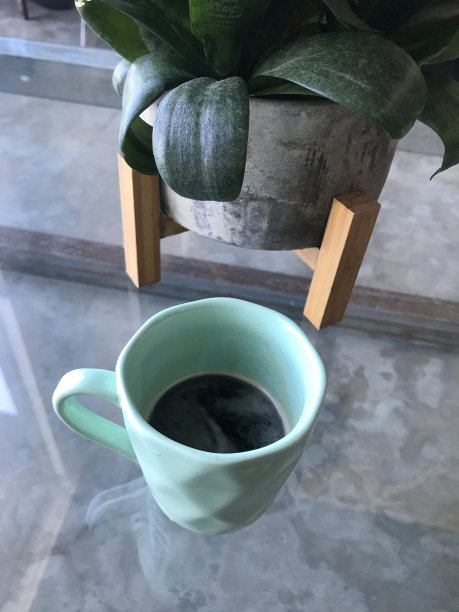 一杯咖啡。蓝色的杯子。一杯咖啡在玻璃背景上。带书的杯子图片下载