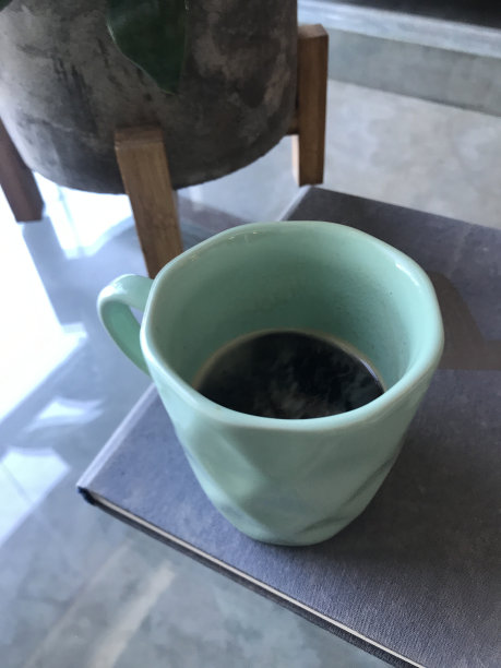 一杯咖啡。蓝色的杯子。一杯咖啡在玻璃背景上。带书的杯子图片下载