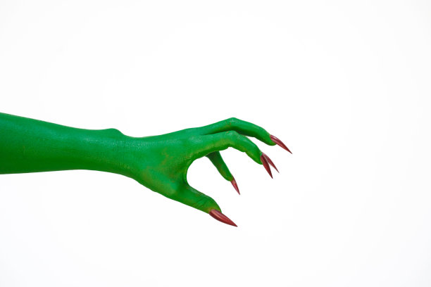 一只长着长指甲的绿色怪物手，孤立在黑暗的背景下，唤起了恐怖和恐惧。非常适合万圣节，这张令人毛骨悚然的图片捕捉到了邪恶和亡灵的本质。图片下载