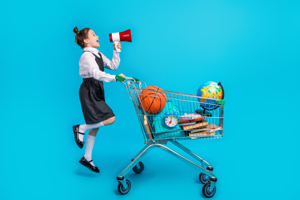 可爱小女孩的全身照片购物车黑色星期五扬声器穿着时尚的校服孤立的蓝色背景图片下载