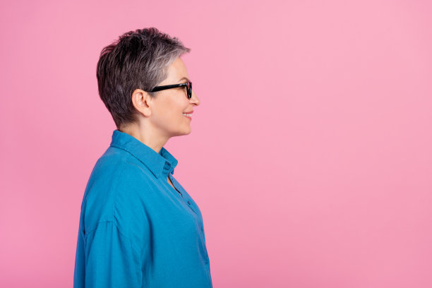 照片肖像上有魅力的资深女性侧面看起来空无一人，穿着时髦的蓝色衣服孤立在粉红色的背景上图片下载