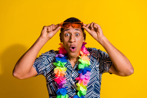 照片帅气印象深刻的家伙穿印花衬衫夏威夷项链handar墨镜孤立的黄色背景图片下载