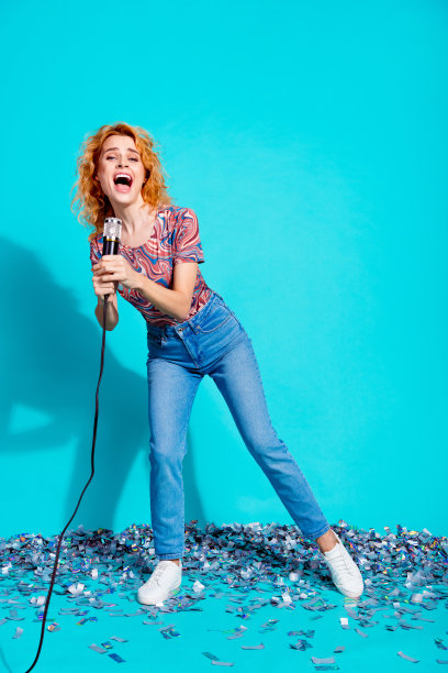 全尺寸垂直照片漂亮的女人拿着麦克风唱歌穿t恤孤立的蓝绿色背景图片下载
