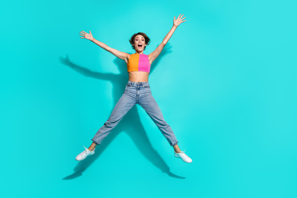 印象深刻的全身照片兴奋的女士穿着五颜六色的顶跳高像星空空间孤立的绿松石色背景图片下载