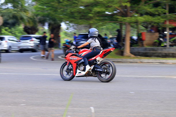 印度尼西亚2024年，骑摩托车的人在城市道路上骑摩托车，背景模糊图片下载