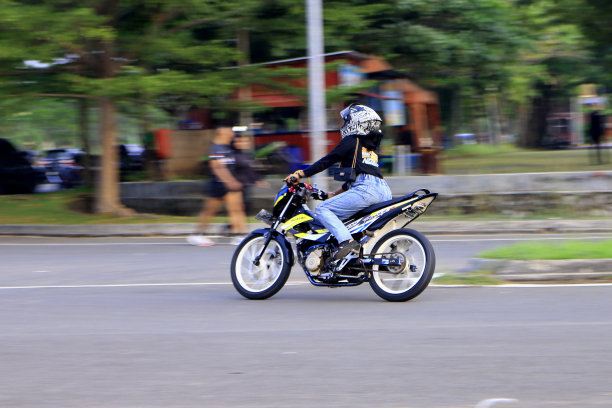 印度尼西亚2024年，骑摩托车的人在城市道路上骑摩托车，背景模糊图片下载